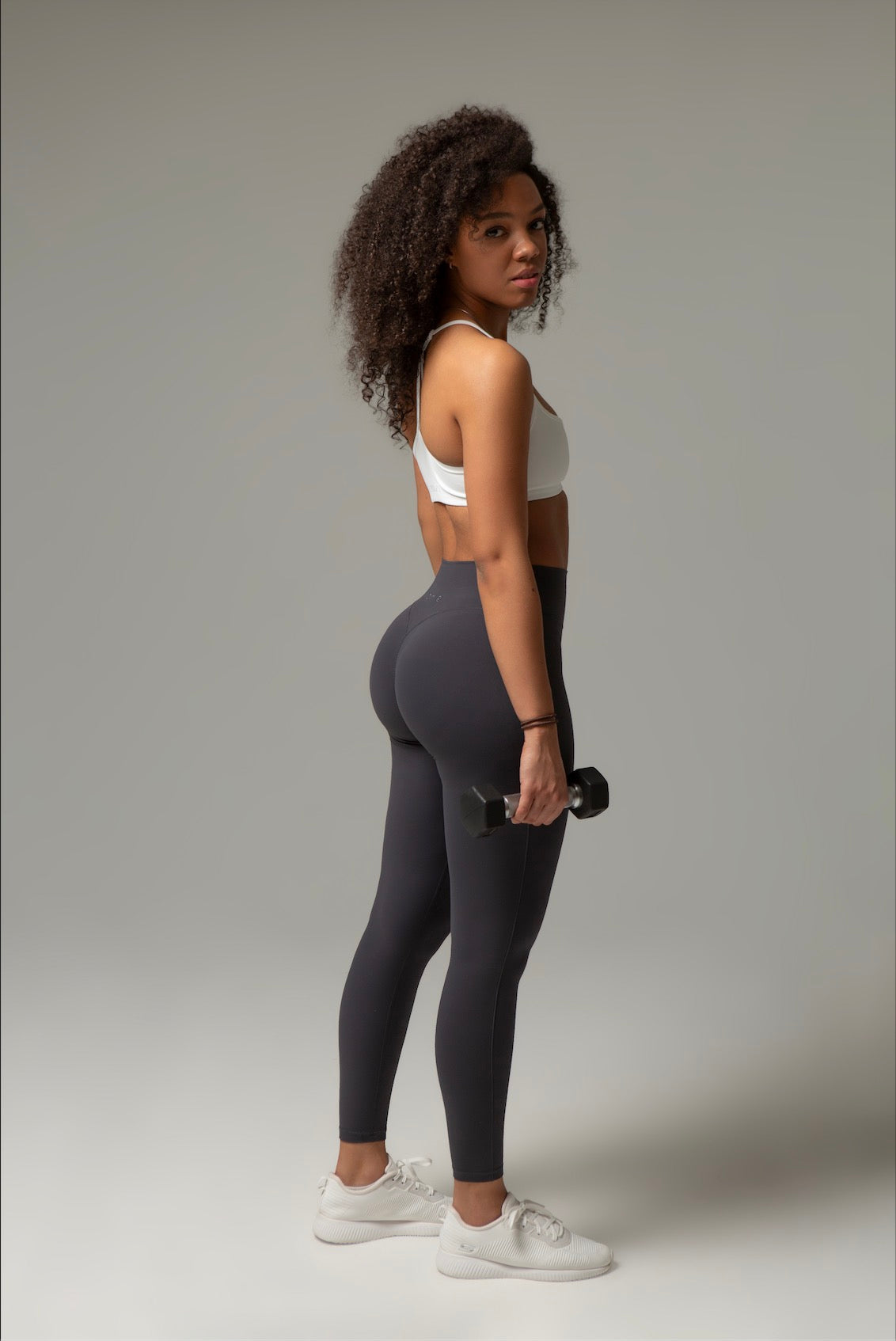 Rückansicht Model im aniri SculptAir Set mit grauen Leggings und Kurzhantel