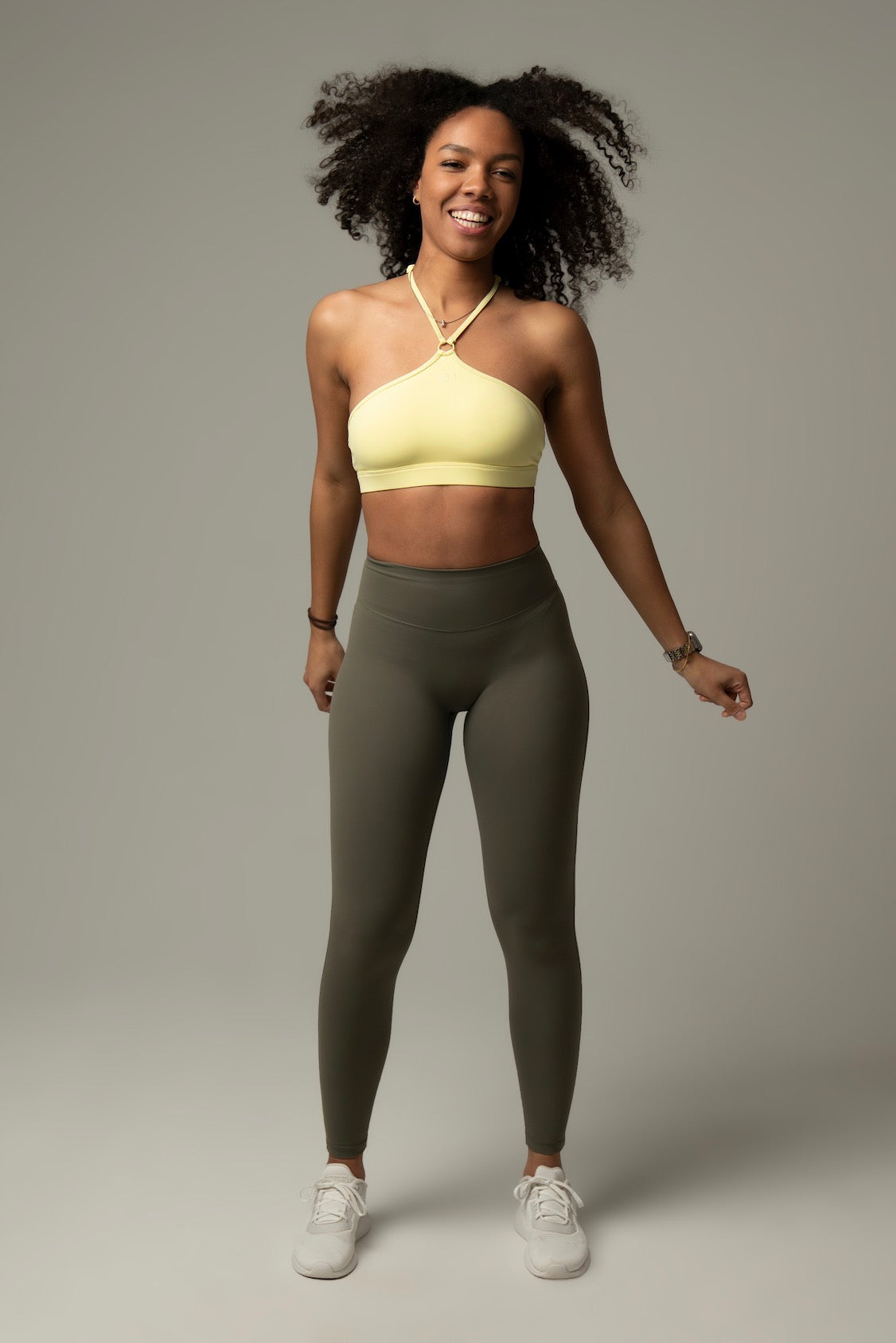 Model im aniri SculptAir One-Shoulder Bra in Gelb – dynamische Pose